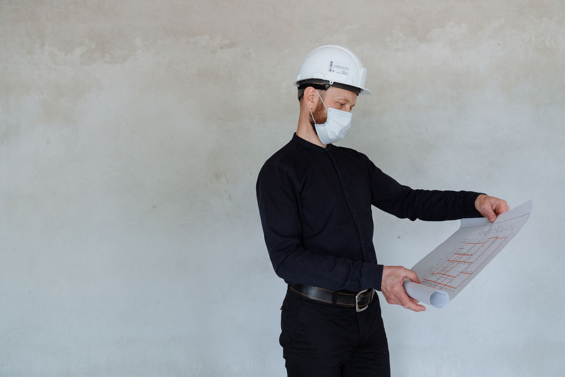 Architekt mit Schutzhelm prüft Baupläne auf der Baustelle