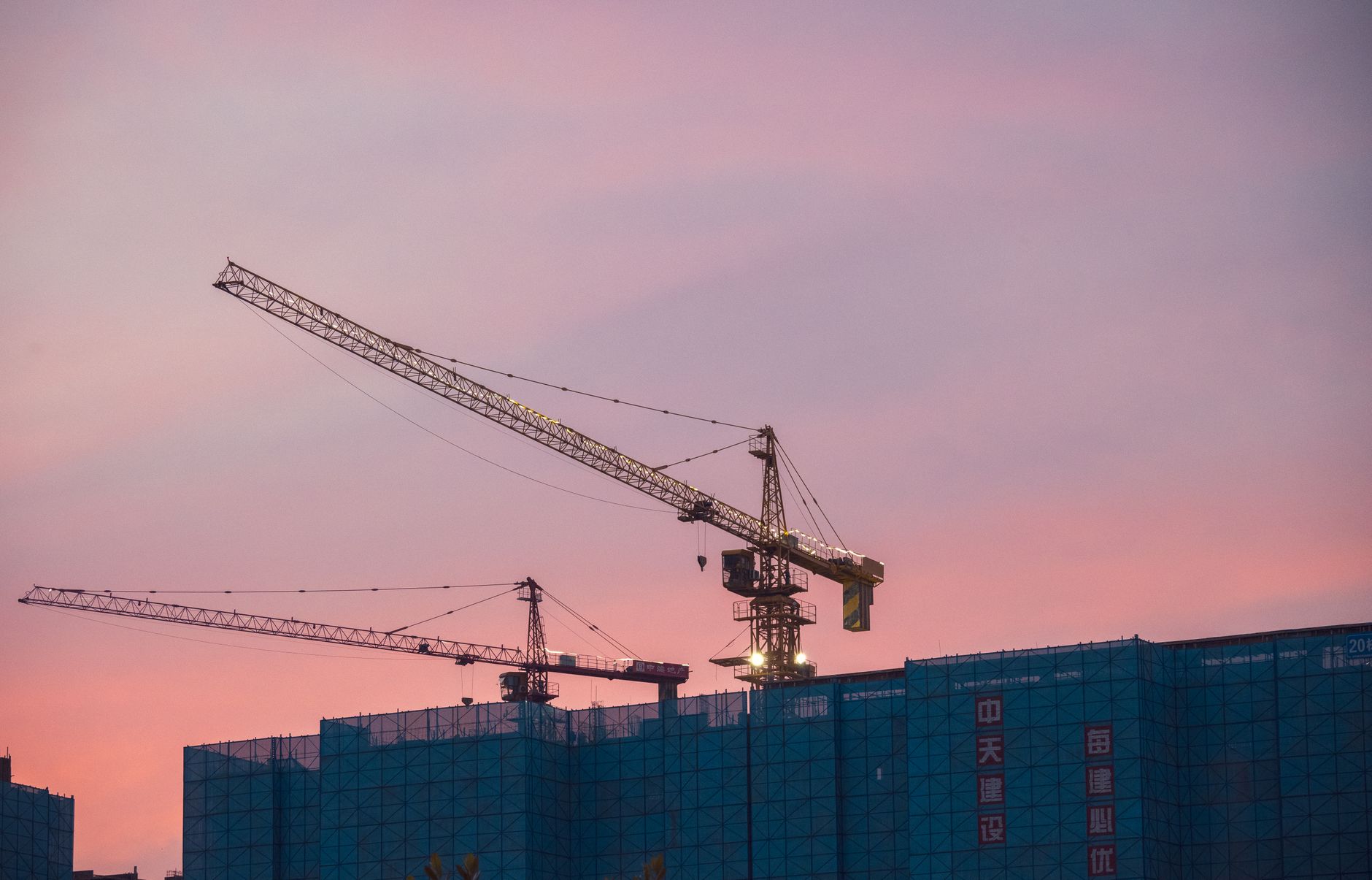 Baukräne über der Skyline bei Sonnenuntergang