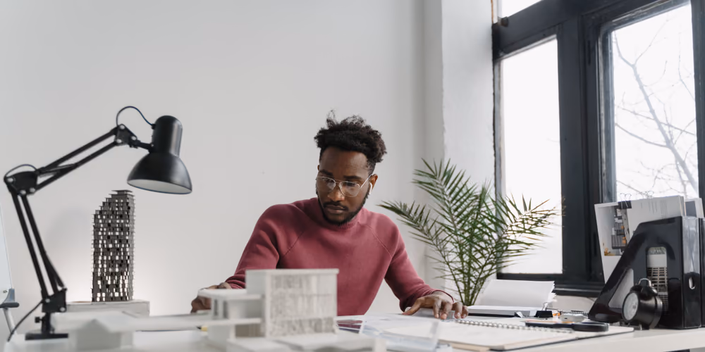 Ein Architekt arbeitet in einem hellen Büro an Plänen und Modellen
