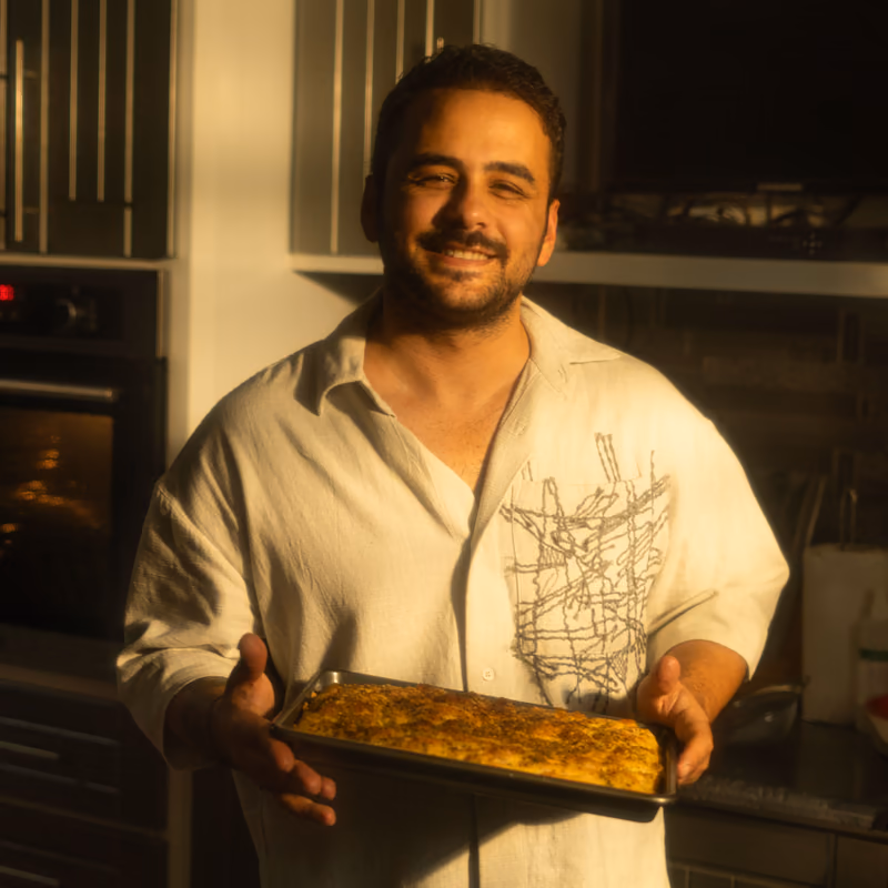 Ein Bäcker hält ein frisch gebackenes Blech in die Kamera