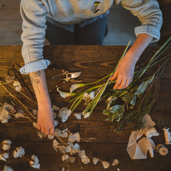Hände einer Floristin binden Blumen auf einem Holztisch