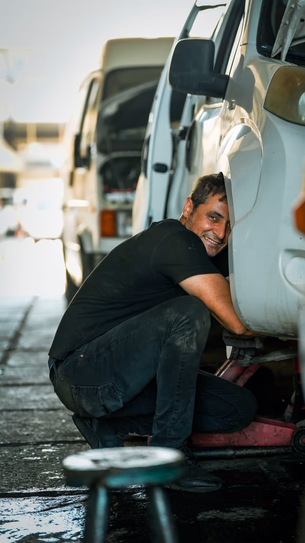 Ein Mechaniker lacht bei der Arbeit an einem Transporter