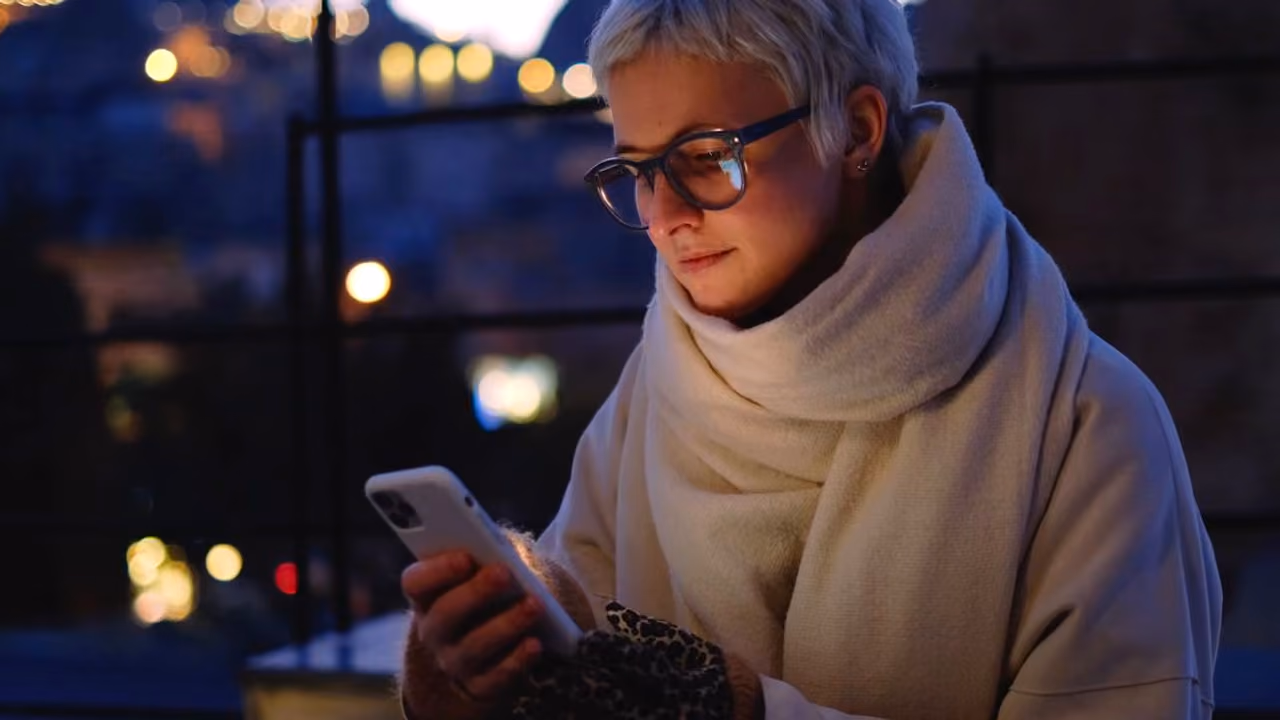 Eine Frau sucht abends in der Stadt auf ihrem Handy